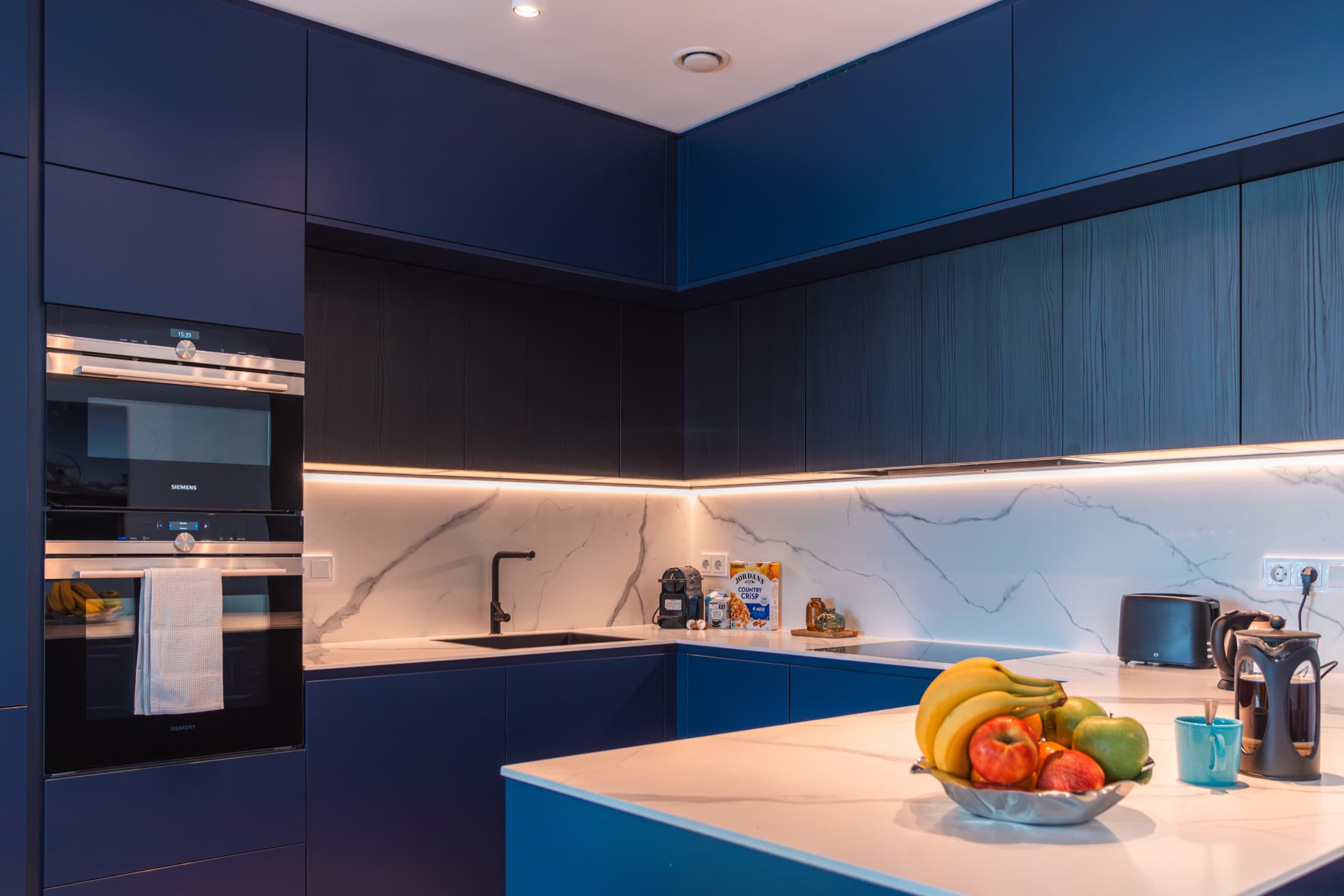 Blue kitchen with white marble splashback at Apartment Linde at Media Bay Kirchberg, Luxembourg